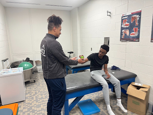 Jones athletic trainer David Robinson helping basketball player Brandon Anderson ‘26.